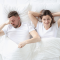 Couple lying in bed with white bedding