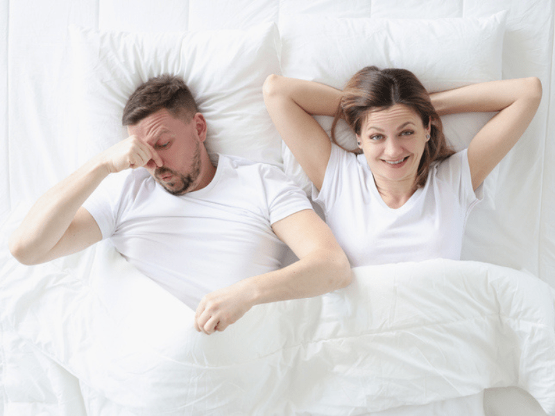 Couple lying in bed with white bedding