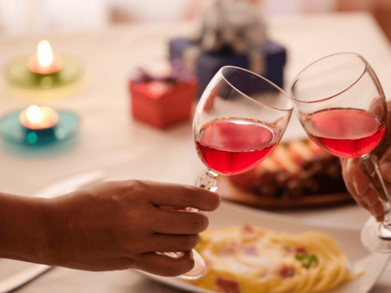 Couples celebrate by drinking red wine over a meal