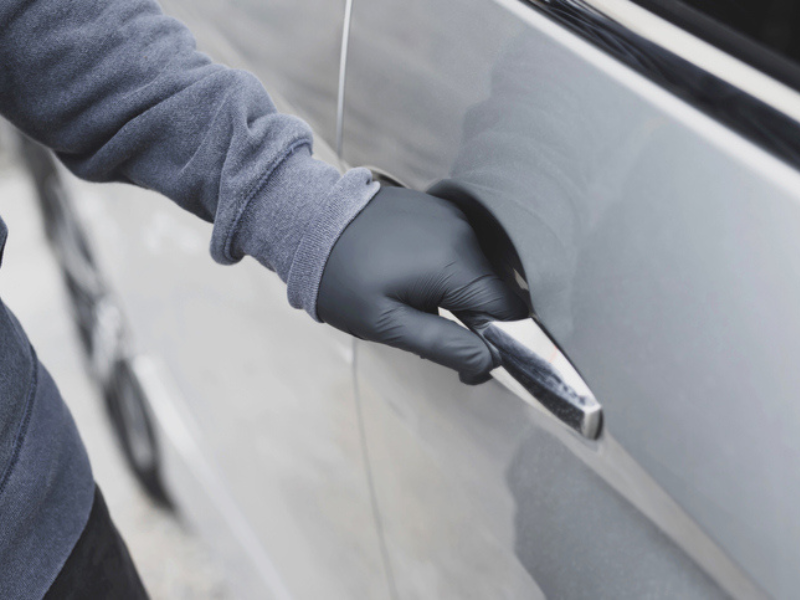 Criminal wearing gloves trying to open a car door