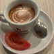 Cup of espresso with slice of tomato