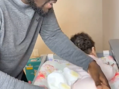 Dad trying to change his baby's diaper