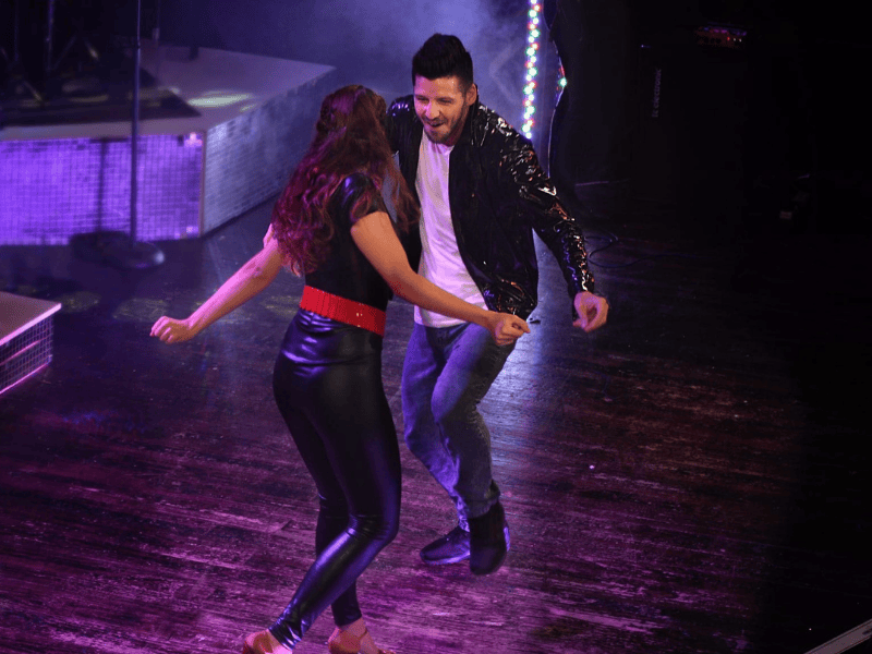 Danny Guselli dancing on stage with a woman