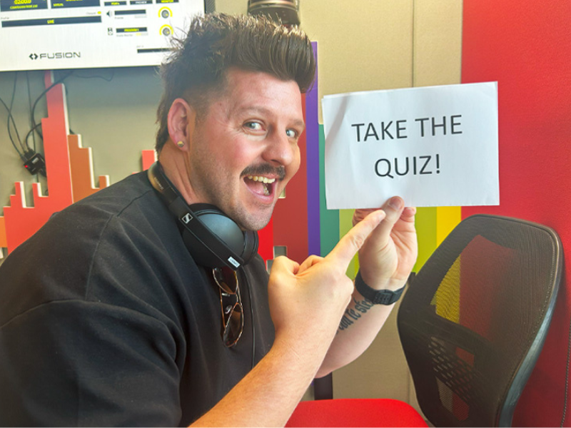 Danny Guselli inside the ECR studios holding a page with copy Take the Quiz