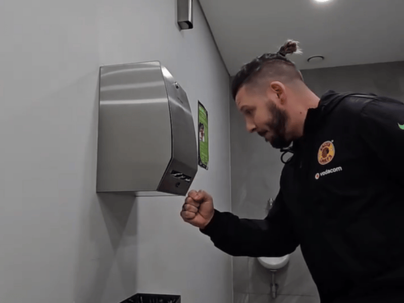 Danny Guselli playing rock paper scissor with a paper towel machine in the mens room