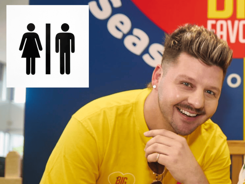 Danny Guselli smiling at the Season of Sharing event with a toilet sign nearby