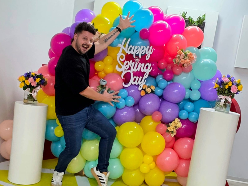 Danny Guselli standing in front of a Spring balloon display