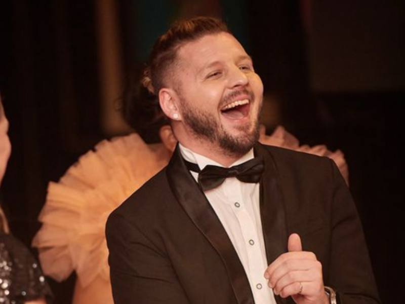 Danny Guselli wearing a tuxedo and laughing out loud