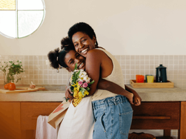 Mother and daughter embrace in a kitchen
