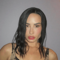 Singer Demi Lovato poses against a grey wall
