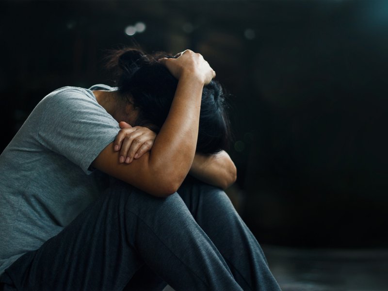 Depressed woman sitting alone on the floor in the dark room
