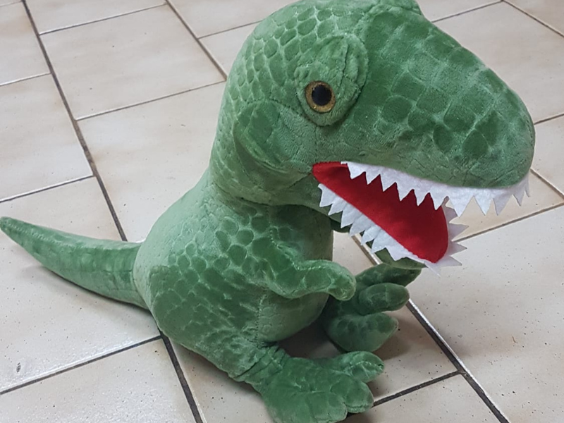 Dinosaur plush toy lying on tiled floor