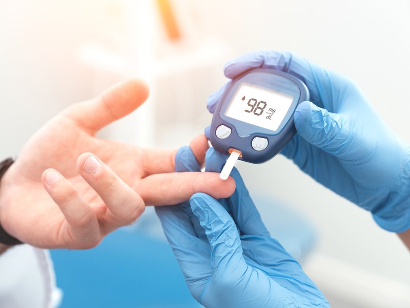 Doctor checking blood sugar level with glucometer