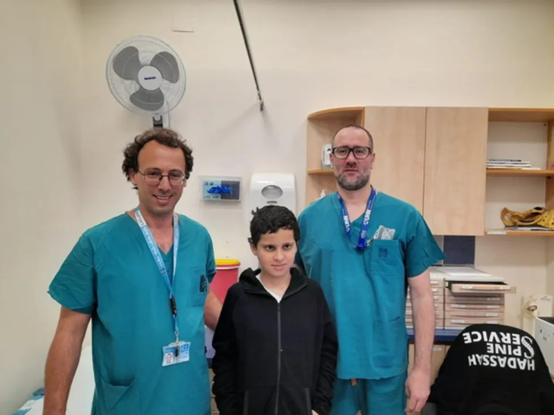 Doctors in scrubs stand with a young boy