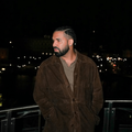 Drake posing on a balcony at night