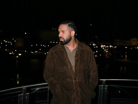 Drake posing on a balcony at night
