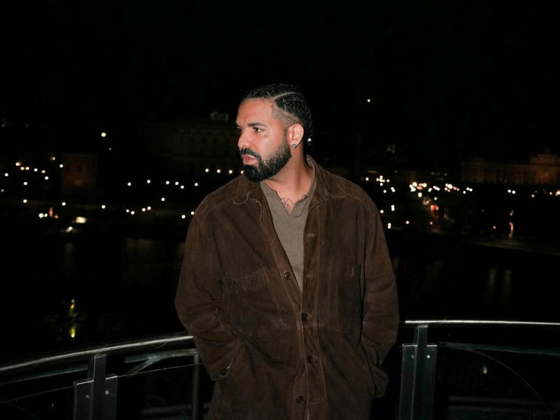 Drake posing on a balcony at night