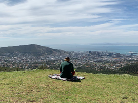 Ed Sheeran sitting on a grassy hill in Cape Town