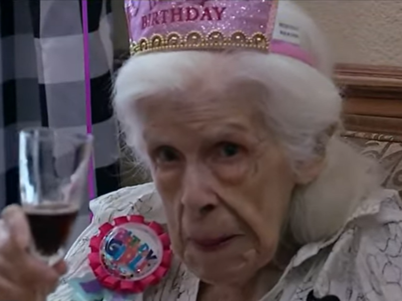 Elderly woman cheering with a glass of alcohol
