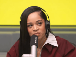 Ella Mai speaks into a mic with an Apple Music logo