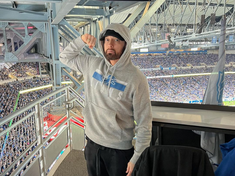 Eminem wearing a grey hoodie and black cap