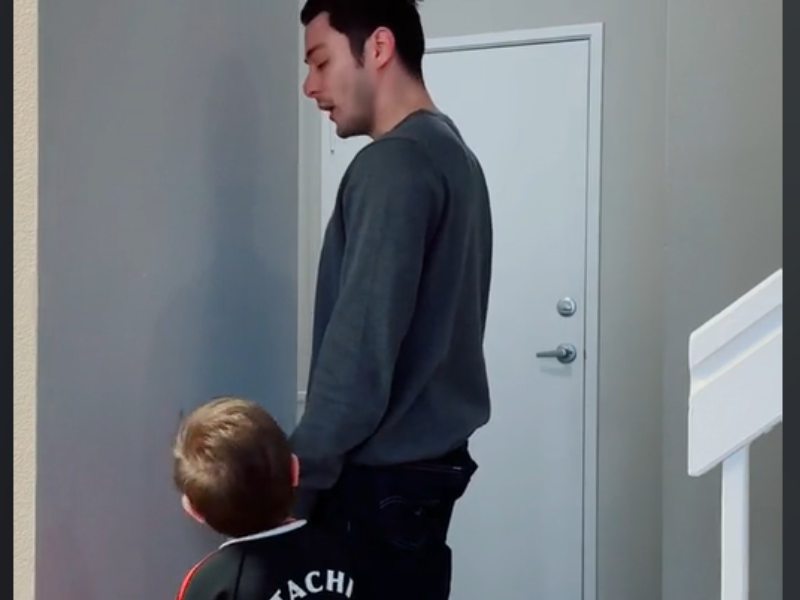 Father and son standing next to each other facing the wall