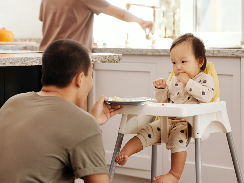 Father playing with baby seated on a high chair