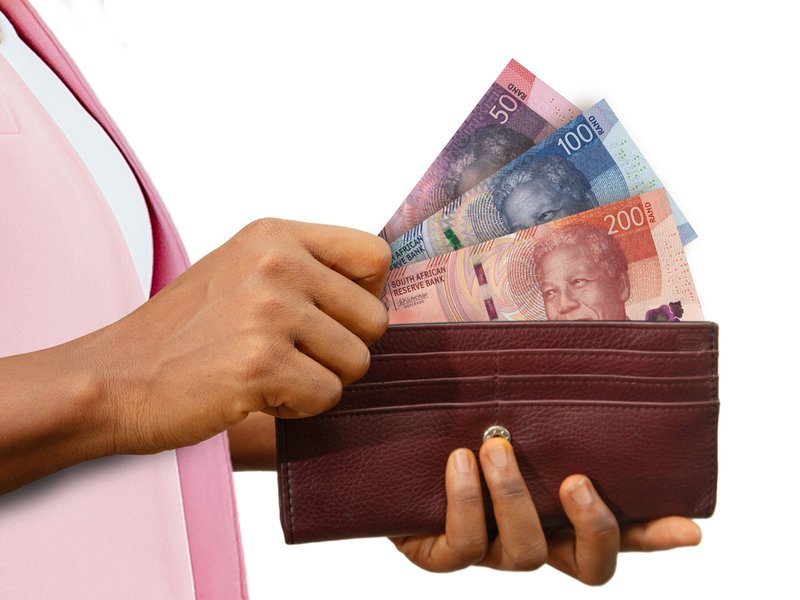 Female Hand Holding brown Purse With South African Rand notes