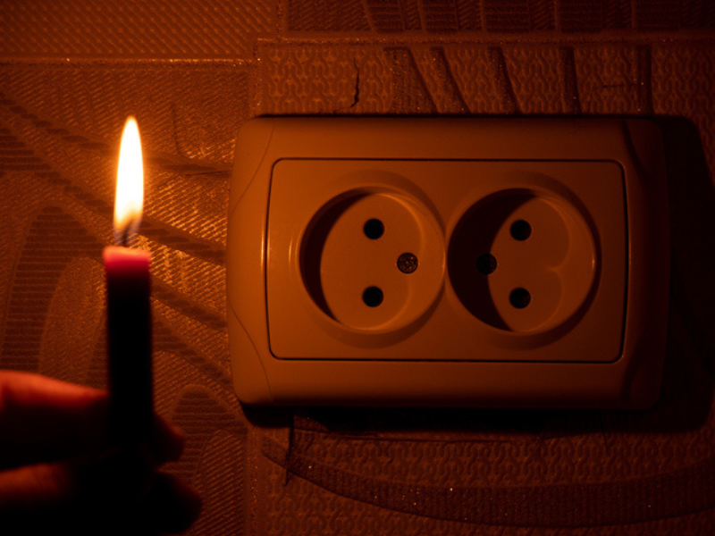 Female hand with candle near a socket on the wall