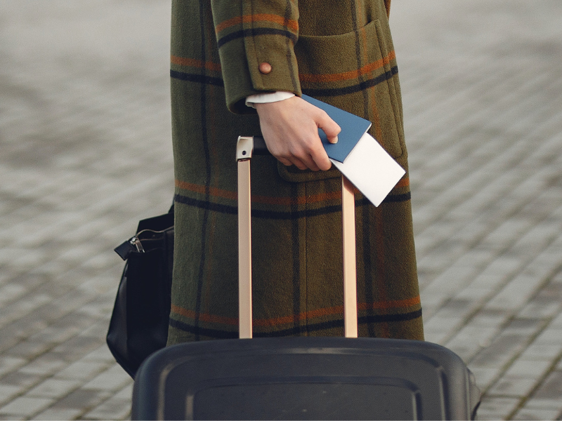 Female traveler walking with suitcase and passport