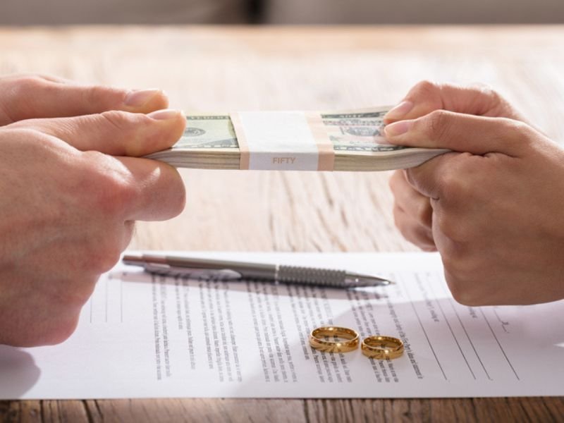 Hands Holding Currency Over The Divorce Agreement