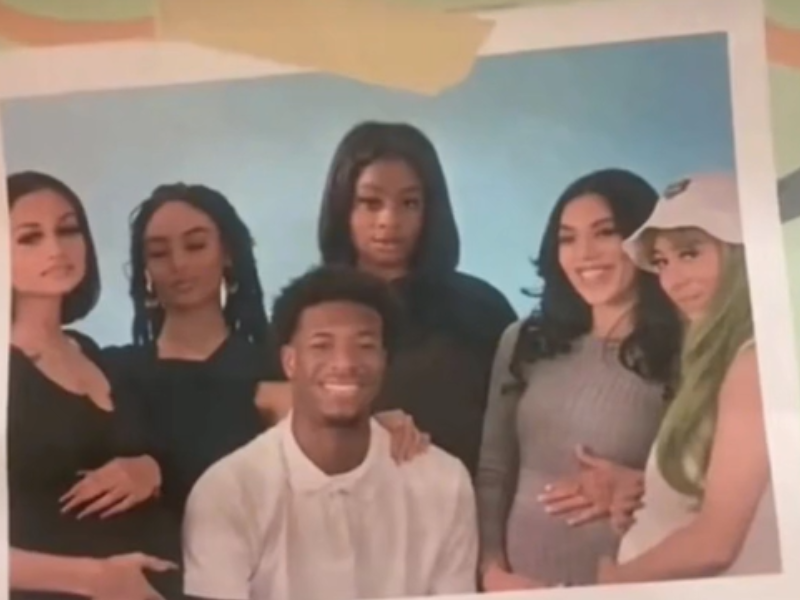Five pregnant women stand with a guy who is smiling