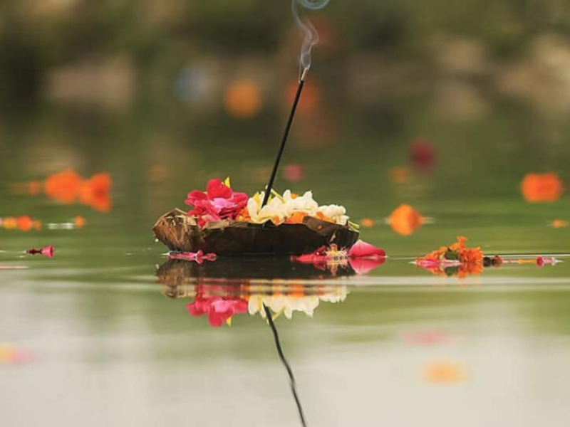 Floating flower with incense stick on river