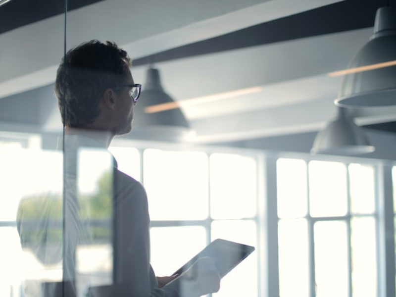 Forman man with a tablet giving presentation in glass office