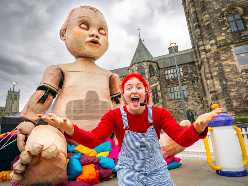Giant baby doll sitting outside an old English building