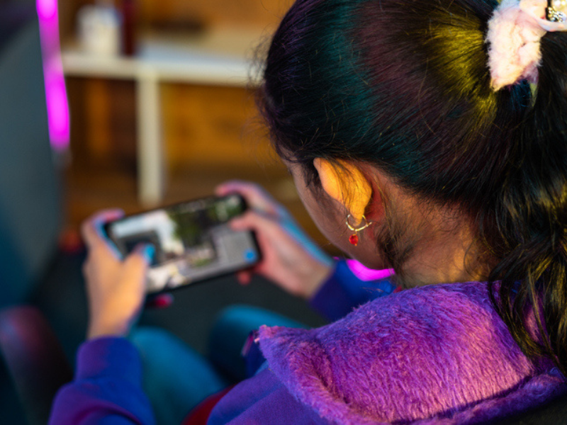 Girl playing live video game on mobile device