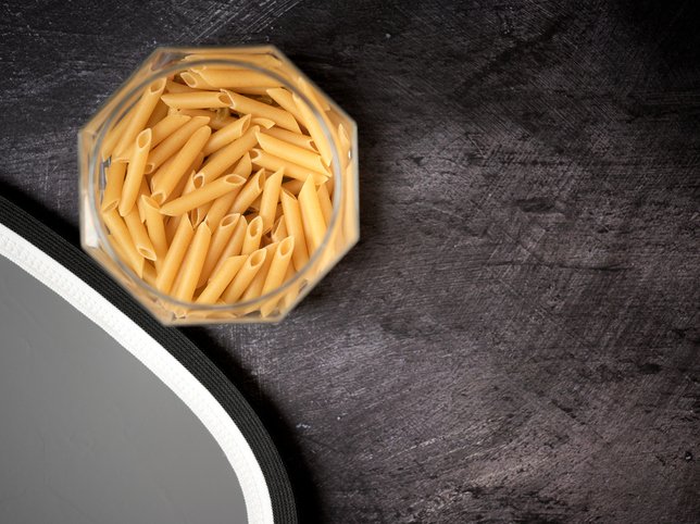 Glass jar with macaroni pasta open on a dark background
