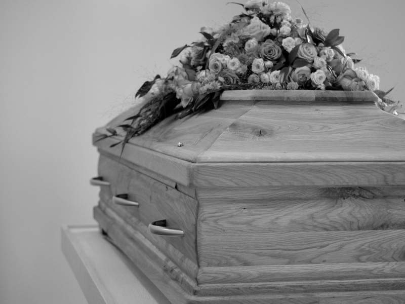 Grayscale of a coffin and flower arrangement on top