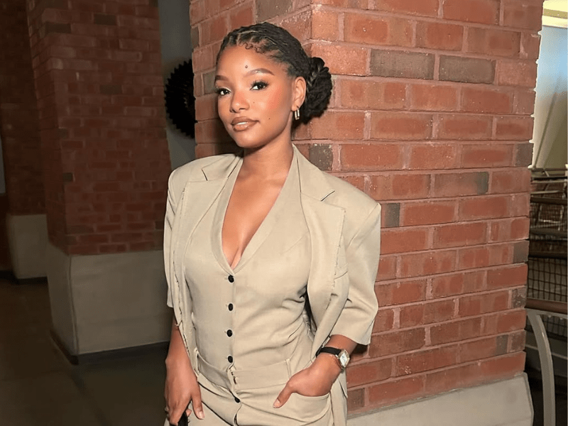 Halle Bailey poses next to a brick wall
