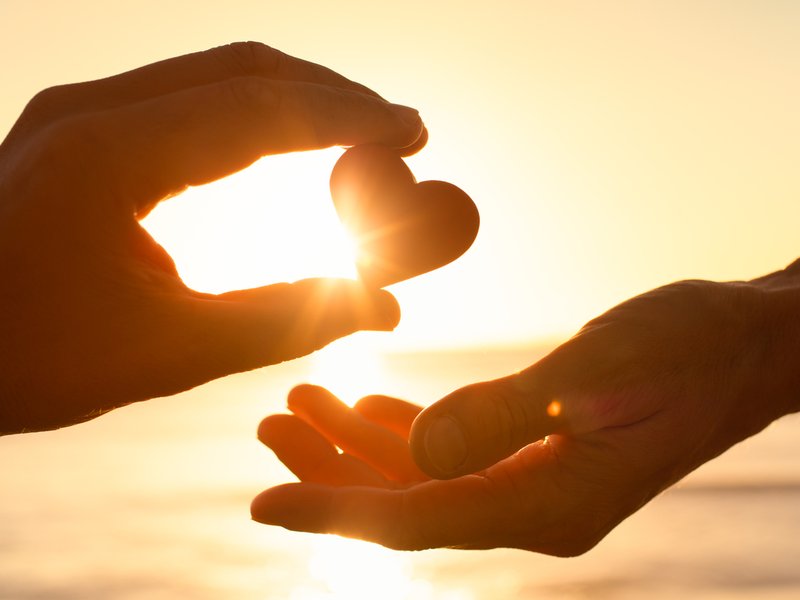 Hand giving heart to another hand