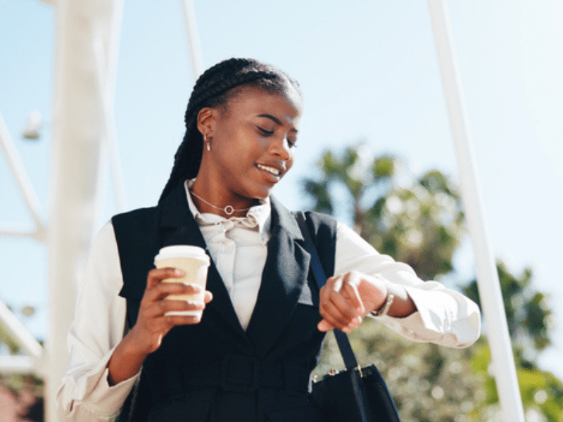 Corporate woman checking her watch while holding a cup of coffee