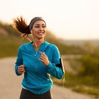 Happy female runner jogging in the morning in nature