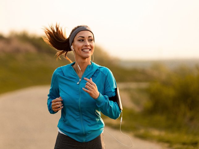 Happy female runner jogging in the morning in nature