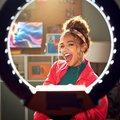 Happy woman with ring light for video recording