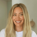 Hilary Duff smiles warmly while wearing a white t shirt