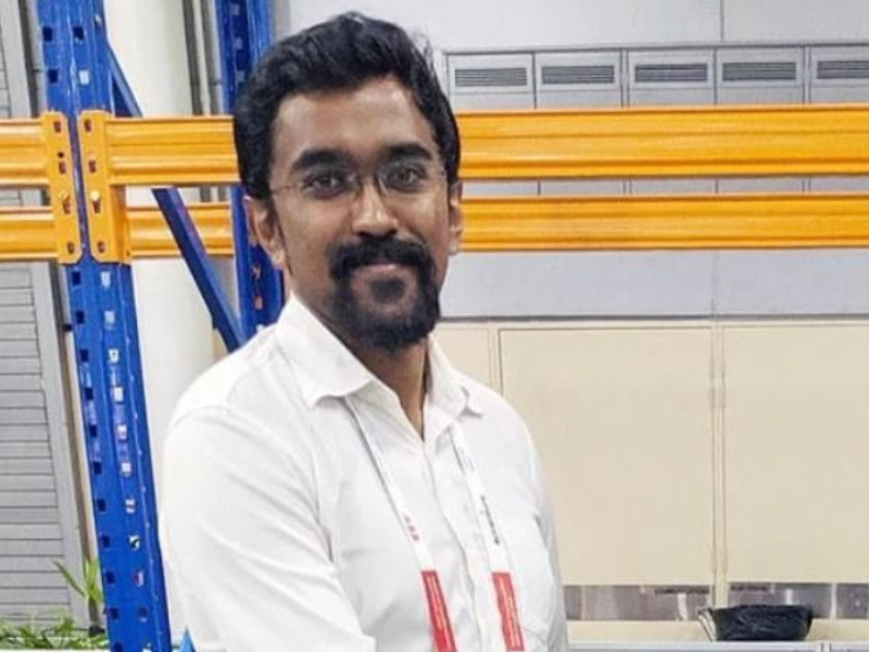 Indian man standing in front of industrial shelving