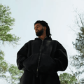 J. Cole wearing a black tracksuit