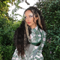 Jade Thirlwall poses next to a leafy green bush