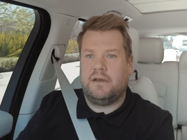 James Corden sitting in the passenger seat of a car with white interior
