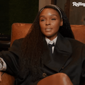 Janelle Monáe sitting on a brown sofa